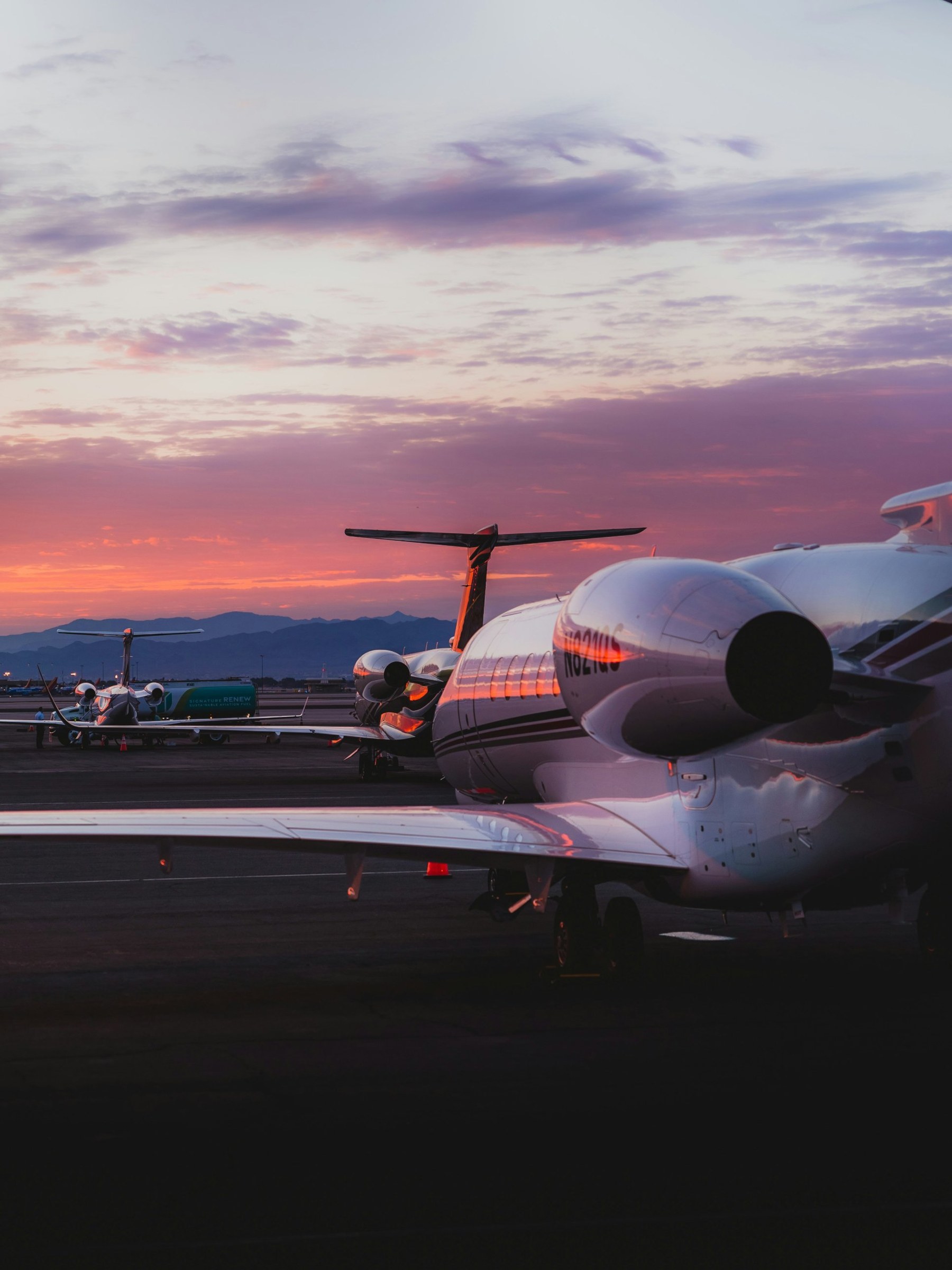 Private jets parked in a row at sunset