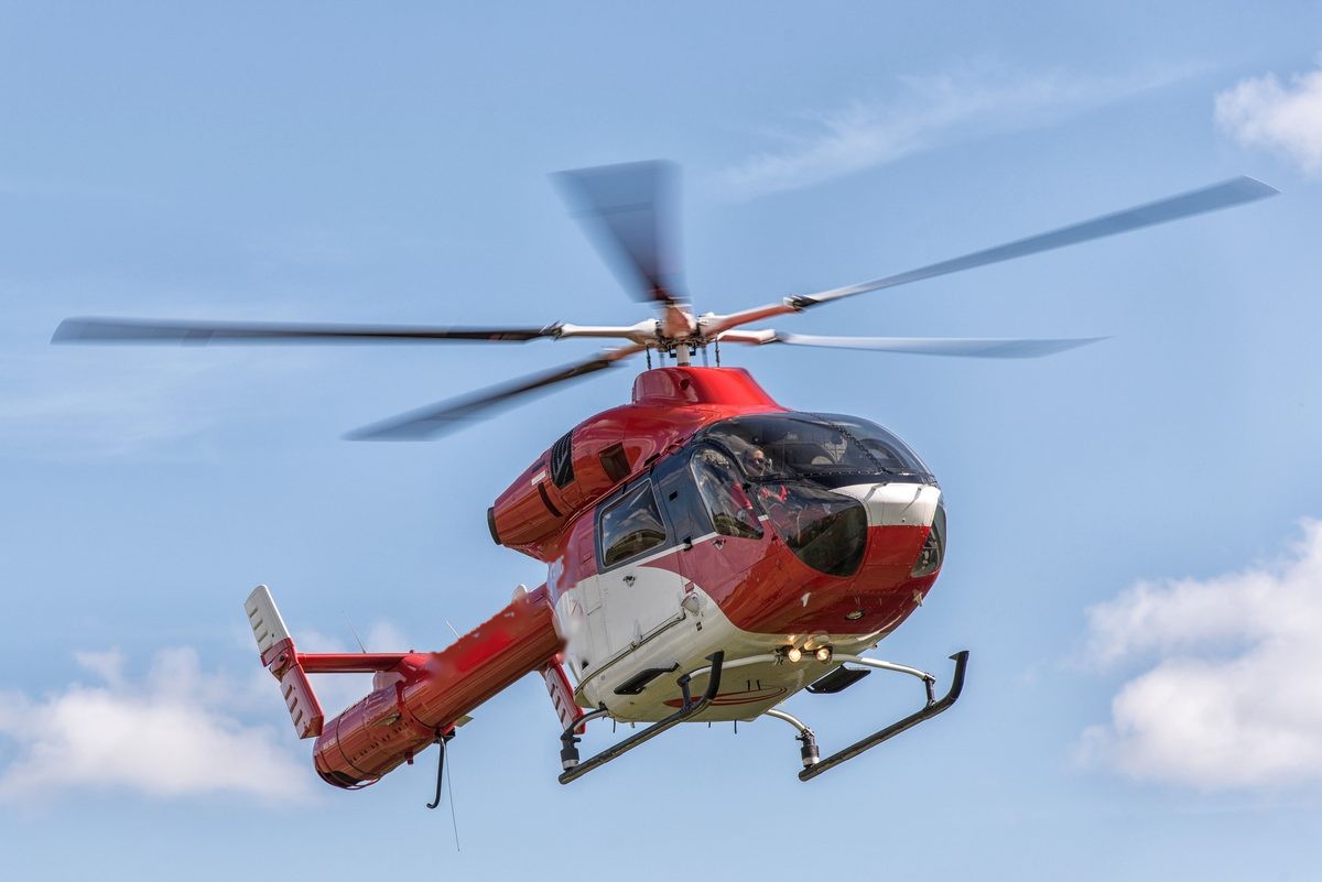 Red and white helicopter in flight against a blue sky
